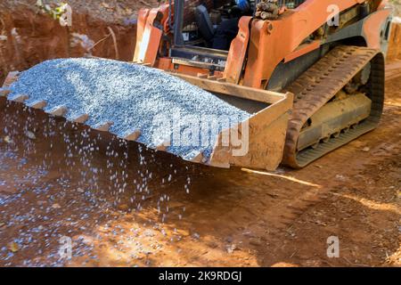 Un godet de pelle hydraulique déforme dans la pierre concassée la pelle hydraulique saisit un godet plein de gravier Banque D'Images