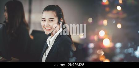 Femme asiatique dans un micro-casque, au bureau, en tant qu'opérateur d'un centre d'appels ou en tant que service clientèle, regardant directement la caméra et souriant Banque D'Images
