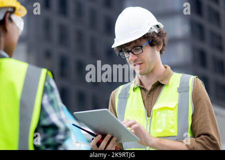 Jeune homme et femme est architecte planification et inspecteur projet et regardant la tablette numérique sur le chantier de construction, ingénieur homme et femme travaillant et Banque D'Images