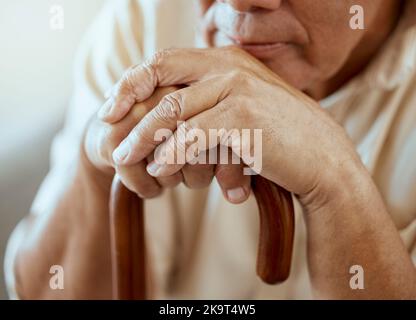 Mains d'un homme âgé sur un bâton de marche, pensée sérieuse et assise, souvenirs à la maison de retraite. Grand-père avec canne en bois, soins aux personnes âgées pour personnes handicapées Banque D'Images