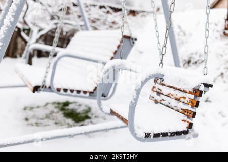 Balançoire blanche en bois recouverte de neige après une forte neige. Hiver givré jour Banque D'Images