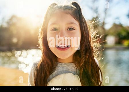 S'amuser au soleil. Portrait d'une adorable petite fille à côté d'un lac. Banque D'Images