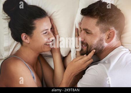 Le bonheur est en train de vous réveiller. Un jeune couple attrayant allongé dans le lit ensemble à la maison. Banque D'Images