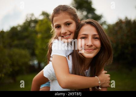 Shes ma sœur et mon meilleur ami. Portrait court d'une jeune fille donnant à sa jeune sœur une promenade en plein air. Banque D'Images