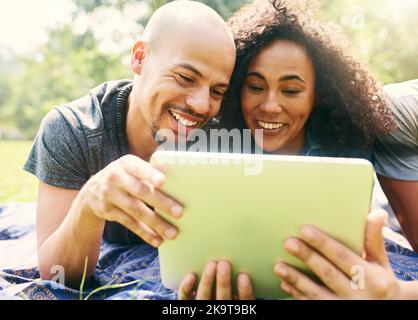 La technologie à l'extérieur. Un jeune beau couple passe la journée dans un parc public. Banque D'Images