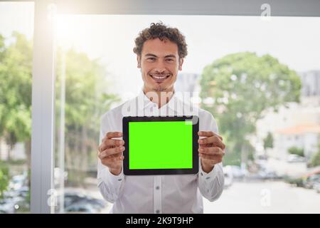 L'application idéale pour vos intérêts professionnels. Portrait d'un beau jeune homme d'affaires tenant une tablette numérique avec un écran vert dans un bureau moderne. Banque D'Images