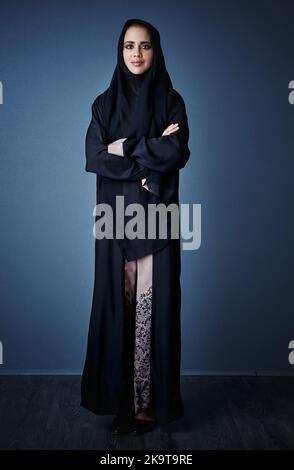 Vous pouvez mettre votre confiance en moi. Portrait complet d'une jeune femme d'affaires attirante debout avec ses bras repliés sur un fond sombre. Banque D'Images