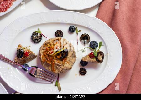 Buffet de banquet. Salade de grenade aux profiteroles farcies et tartelettes dans une assiette isolée sur fond blanc. En-cas pour les fêtes. Banque D'Images