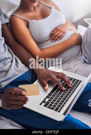 Nous nous sommes assurés que notre bébé obtient le meilleur. Un jeune couple faisant quelques achats en ligne avec une carte de crédit. Banque D'Images