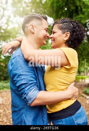 Leur amour est clair pour tous. Un jeune couple affectueux qui s'embrasse en se tenant dehors du parc. Banque D'Images