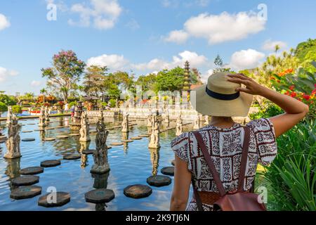 Femme voyageur portant une robe blanche et un chapeau de paille au temple de Taman Tirtagangga à Bali, en Indonésie, par une journée ensoleillée Banque D'Images