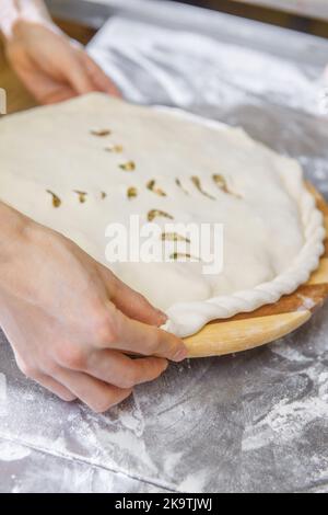 Les mains fermant la tarte ossète farcie de viande hachée sur la table métallique de la cuisine du restaurant. Banque D'Images