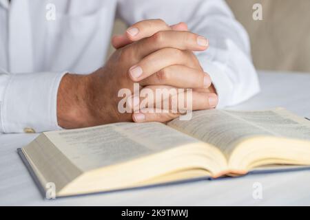 Fermez les mains du joueur sur la Sainte Bible ouverte. Homme priant le fond. Banque D'Images