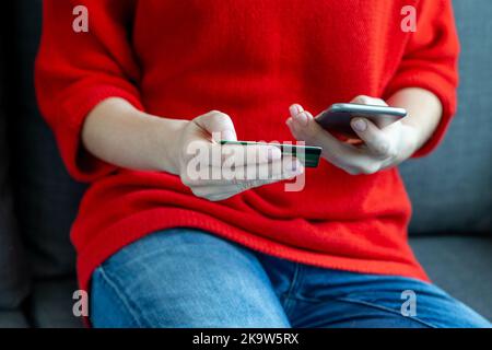 Gros plan des mains féminines faisant l'achat en ligne via smartphone, carte dans la main Banque D'Images