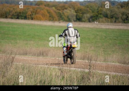 Un cycliste à moteur (motard) qui fait rouler sa moto tout-terrain le long d'une piste de pierre sur la plaine de Salisbury, dans le Wiltshire Banque D'Images