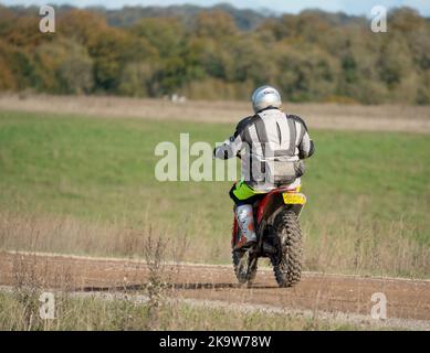 Un cycliste à moteur (motard) qui fait rouler sa moto tout-terrain le long d'une piste de pierre sur la plaine de Salisbury, dans le Wiltshire Banque D'Images