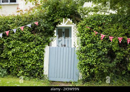 BUCKINGHAMSHIRE, Royaume-Uni - 03 juin 2022. Extérieur de la maison avec portail de jardin bleu, porte avant et haie Banque D'Images