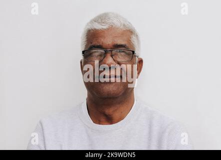 Homme expérimenté et confiant regardant la caméra tout en se tenant sur un fond blanc. Portrait d'un homme mature portant des lunettes. Banque D'Images