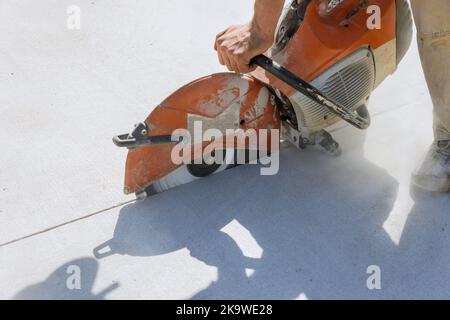 Travailler sur un trottoir en béton à l'aide d'une scie à lame de diamant pour couper le béton Banque D'Images