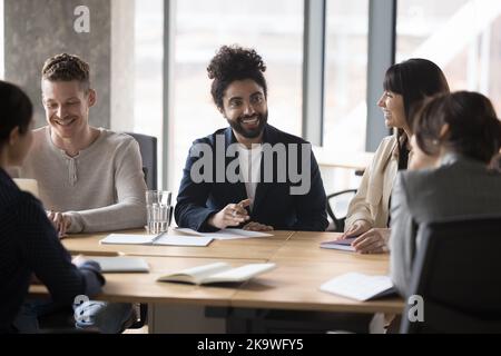 Homme d'affaires indien souriant discutant avec des clients lors d'une réunion formelle Banque D'Images