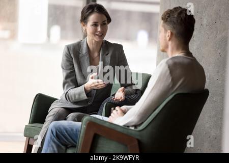 Deux collègues qui parlent assis dans des fauteuils se rencontrent dans le hall du bureau Banque D'Images