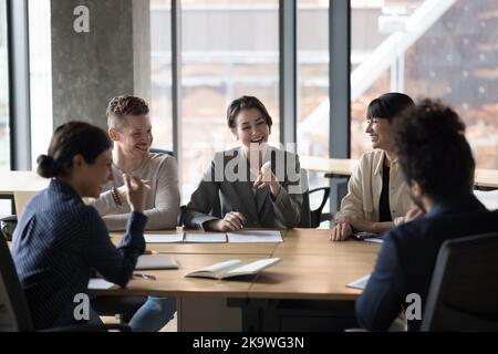Les gens d'affaires heureux et variés rient, font des brainstorming, discutent des idées d'affaires au bureau Banque D'Images