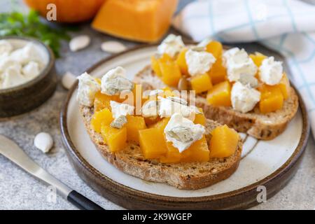 Nourriture saine, hors-d'œuvre végétarien. Des sandwichs ouverts au pain aux grains entiers avec de la citrouille épicée et du fromage feta sur une table en pierre. Banque D'Images