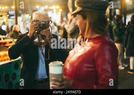 Joyeux couple senior s'amusant avec une caméra vintage sur le marché de Londres - Focus sur les mains de l'homme Banque D'Images