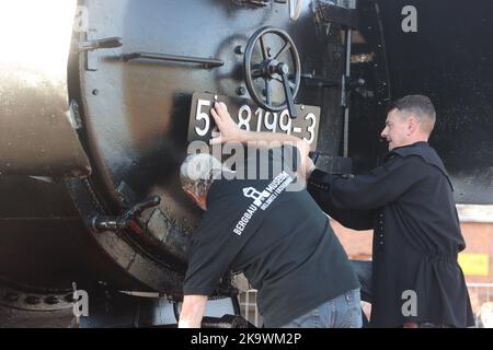 Oelsnitz, Allemagne. 30th octobre 2022. Andreas Quitschau (l) et Heiko Vieweger du Musée minier montent la dernière plaque signalétique sur l'avant d'une locomotive à vapeur de classe 52, année de fabrication 1944, sur le terrain du Musée minier comme un baptême symbolique. Après plus d'un an de restauration, la locomotive brille dans une nouvelle splendeur. Credit: Bodo Schackow/dpa/Alay Live News Banque D'Images