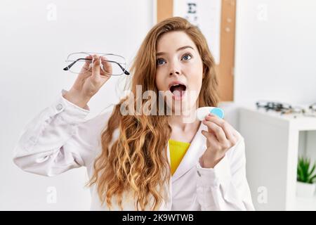 Jeune opticienne caucasienne tenant des lunettes et des lentilles de contact à la clinique en colère et folle criant frustrée et furieuse, criant avec la colère lo Banque D'Images