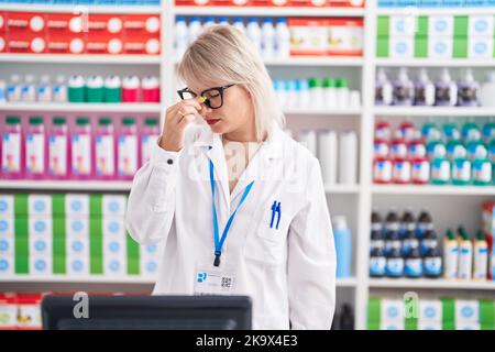 Jeune femme caucasienne travaillant à la pharmacie pharmacie fatigué frottant le nez et les yeux sensation de fatigue et de maux de tête. Concept de stress et de frustration. Banque D'Images