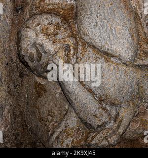 Un monstre grinçant mord la queue d'une autre bête mythique sous les pieds d'un ancien martyr chrétien d'école. Détail carré du mal se mangeant symboliquement dans la sculpture romane de 1100s. Au-dessous de la statue de la colonne à Saint Pastor, 13 ans, dans le portail nord de la Basilique Saint-Just, consacrée en 1200 av. J.-C., à Valcabrère, Occitanie, sud-ouest de la France. Banque D'Images