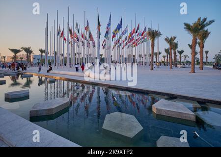 Vue de la corniche de Doha au coucher du soleil montrant les drapeaux des pays participants et la fontaine en premier plan avec les gens qui célèbrent. Préparation du Qatar pour la FIFA Banque D'Images