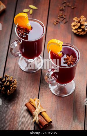 Deux verres de vin chaud avec des oranges et des épices sur fond de bois. Boisson chaude d'automne avec vin, fruits et épices. Boisson au vin de fête Banque D'Images