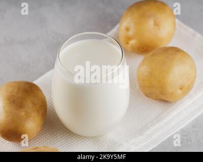 Lait de pomme de terre boisson non laitière de remplacement. Lait sans lactose et pommes de terre crues sur fond gris. Concept de lait alternatif Banque D'Images