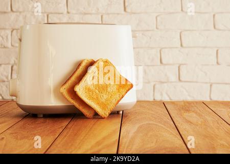 Grille-pain électrique blanc et tranches de pain grillées dans la cuisine moderne. Les technologies de cuisine et de décoration d'intérieur Banque D'Images