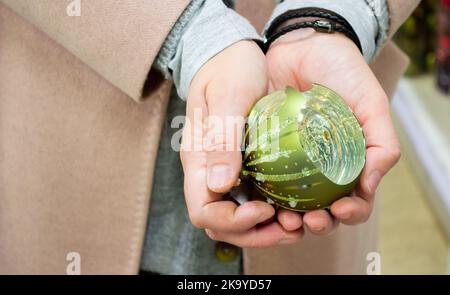 Gros plan d'un sapin de Noël vert en verre cassé dans les mains de la femme. Banque D'Images