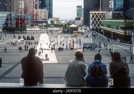 1990s photo d'archive de personnes assises sur des marches regardant la vue de la Défense vers l'Arc de Triomphe. Banque D'Images