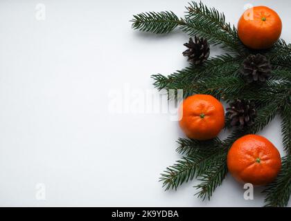 L'esprit et l'odeur de Noël, les décorations de la nature : branches de sapin, cônes, et mandarines d'orange sur fond blanc avec espace pour le texte. Banque D'Images