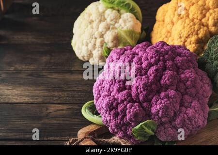 Chou-fleur de Colorfu. Diverses sortes de chou-fleur sur fond de bois ancien. Cabages de couleur violet, jaune, blanc et vert. Brocoli et romanesco. AGR Banque D'Images