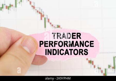 Concept commercial et commercial. Sur le fond du tableau de cotation, un homme tient un signe avec l'inscription - indicateurs de performance de Trader Banque D'Images