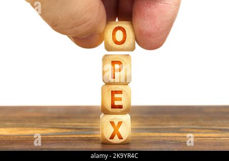 Concept d'entreprise. Un homme met des cubes de bois sur la table avec l'inscription - OPEX Banque D'Images