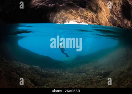 La moitié au-dessus, la moitié inférieure de la diver (MR) à l'entrée d'une caverne qui brise la surface de l'île de Gato, la mer de Bohol, Philippines, Southea Banque D'Images