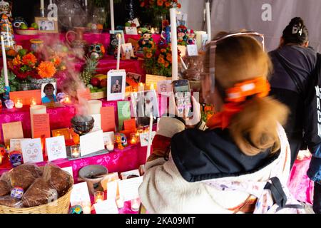 New York, NY, États-Unis. 30th octobre 2022. Mano a Mano: Culture mexicaine sans frontières (Cultura Mexicana Sin Fronteras) a organisé une célébration Dia de Muertos à l'église Saint-Marc In-the-Bowery, avec un autel commémoratif d'offrandes, de photographies et de souvenirs écrits, ainsi que de la nourriture, de l'artisanat et des divertissements mexicains. Une femme photographie une carte commémorative qu'elle vient de placer sur l'autel. Credit: Ed Lefkowicz/Alay Live News Banque D'Images