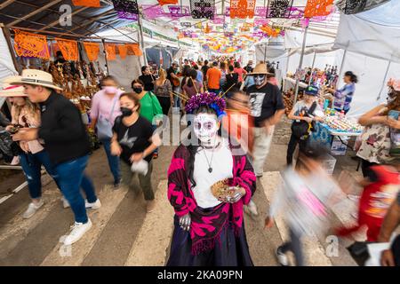 Morelia, Mexique, 30 octobre 2022, les festivités du jour des morts à Michoacan incluent le festival de la Catrina à Capula, où ce modèle en direct est stationnaire pendant que les gens marchent. Les squelettes ou crânes élégamment habillés connus sous le nom de catrinas sont devenus populaires pendant la Révolution mexicaine au début des années 1900 comme une satire de la classe supérieure moralement décadente. Brian Overcast/Alamy Live News Banque D'Images