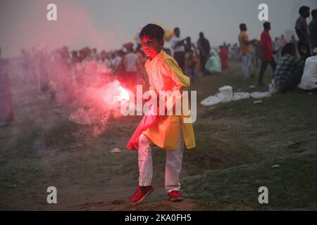 Noida, Inde. 30th octobre 2022. Un garçon brûle un péroneur sur les rives de la rivière Yamuna pendant le festival Chhath Puja à Noida. Les prières pendant la puja de Chhath sont consacrées à la déité solaire, Surya/ Soleil, pour montrer la gratitude et la gratitude. Crédit : SOPA Images Limited/Alamy Live News Banque D'Images