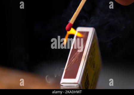 Le match-stick se déclenche sur la boîte d'allumettes en gros plan au ralenti. Le match était allumé, un feu flamboyant. Cliché d'une correspondance enflammée avec un arrière-plan noir. Banque D'Images