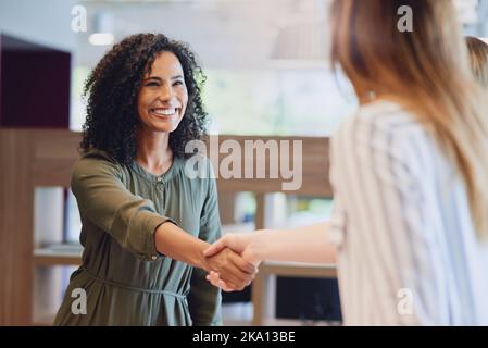 C'est un plaisir de vous rencontrer enfin. Prise de vue en contre-plongée de deux jeunes femmes d'affaires qui se secouent pendant une réunion dans la salle de réunion. Banque D'Images