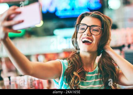 Une belle jeune femme qui prend un selfie dans un restaurant. Banque D'Images