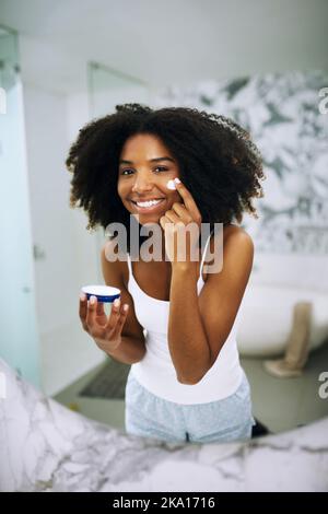 Je ne donne que la meilleure peau. Portrait d'une jeune femme attrayante appliquant un hydratant sur son visage à la maison. Banque D'Images